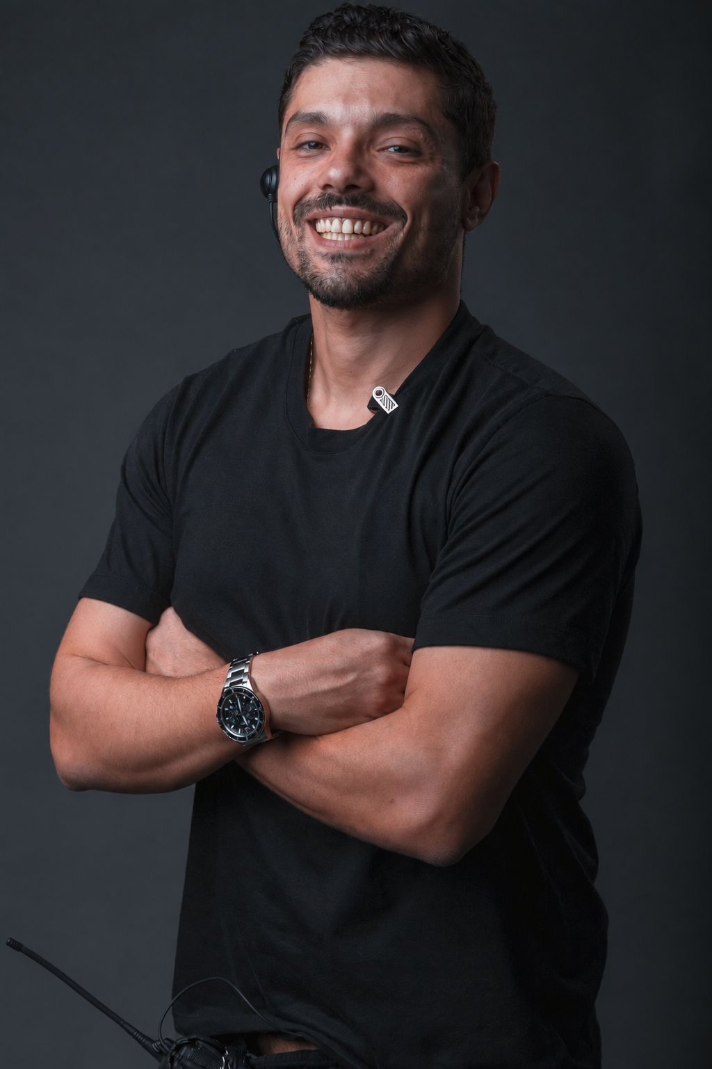 Victor Luporini de braços cruzados, retrato de estúdio em fundo escuro